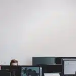 man in black jacket sitting beside black flat screen computer monitor